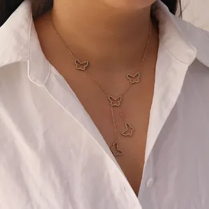 Detailed view of a gold butterfly tassel necklace with rhinestones on a white shirt