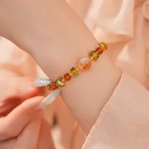 Vue rapprochée d'un bracelet de perles de verre ambre et vert avec des accents dorés