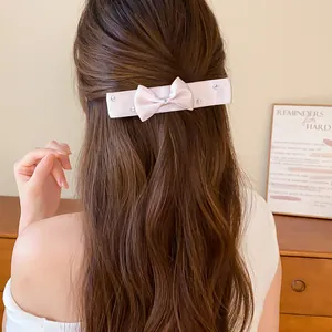 Detail of a pink satin bow hair clip with elegant rhinestone embellishments on hair