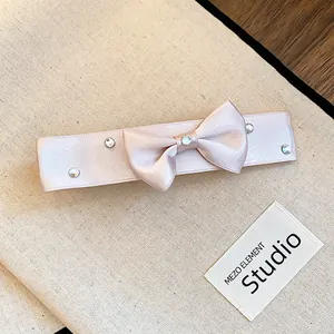 Detailed close-up of a pink satin bow hair clip decorated with sparkling rhinestones.