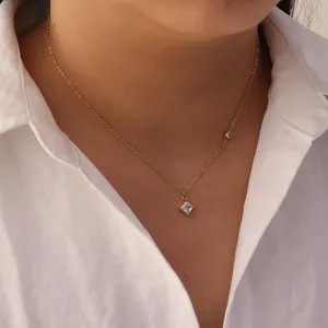 Close-up of a minimalist stainless steel gold necklace with a square white gemstone pendant