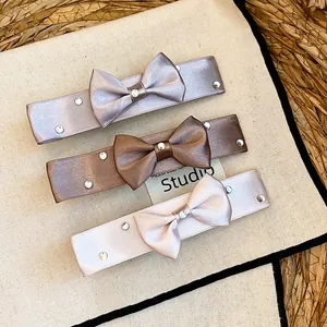 Close-up of three different colored satin ribbon bow hair clips with elegant rhinestone details