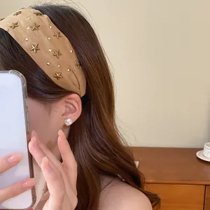 Primer plano de una diadema vintage de tela marrón con tachuelas de estrellas en modelo.