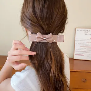 Elegant champagne satin bow hair clip with sparkling rhinestones shown on model's hair