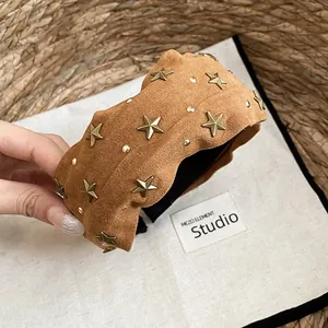 Primer plano detallado de una diadema ancha de tela camel con tachuelas de estrellas doradas