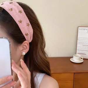 Detalle de diadema de tela rosa con tachuelas de estrellas doradas de estilo retro
