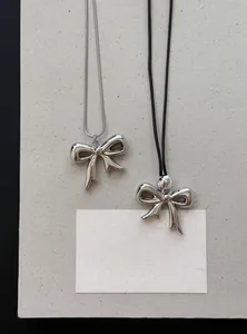Detail van stijlvolle strikhanger halskettingen met zilveren ketting en zwart koord