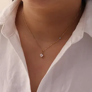 Detail of minimalist stainless steel necklace with square white diamond pendant on model