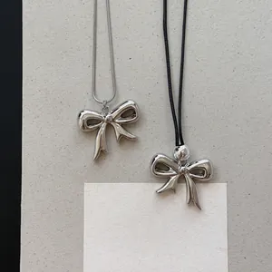 Detailweergave van twee zilveren strikhangers aan slangenketting en zwart koordje