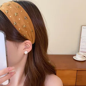Vista detallada de una diadema vintage de tela marrón con estrellas metálicas en una modelo