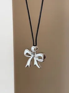 Gedetailleerde close-up van een glanzende zilveren strikhanger aan een zwart koord ketting
