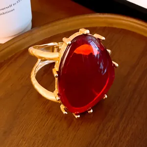 Makrodetail eines großen roten dreieckigen Harzsteins auf einem goldenen Armreif