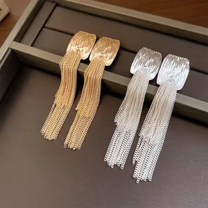 Close-up of elegant gold and silver pleated square earrings with long tassel fringe