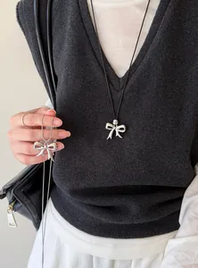 Detail van de zilveren strikhanger ketting aan een zwart koord en zilveren ketting.
