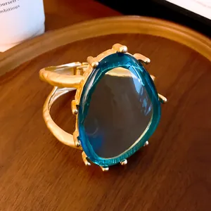 Detailansicht eines goldenen doppellagigen Armreifs mit einem großen blauen Kunststein