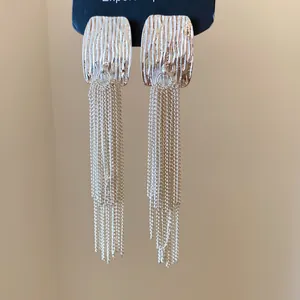 Macro detail of French style wrinkled square earrings with elegant long silver tassel chains