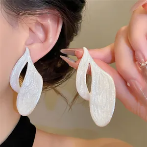 Close-up of white drip oil earrings showing unique texture and stylish design on ear.