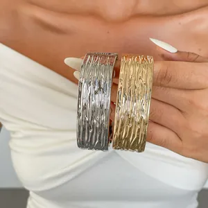 Detailopname van gouden en zilveren armbanden met een unieke geplooide metaaltextuur.