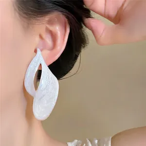 Detailed view of white textured oil drip earrings with pearlescent finish