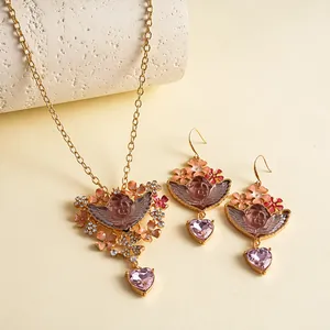 Detailoverzicht van vintage engel en hart hangerset met roze bloemen en fonkelende kristallen