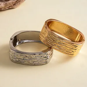 Macro-opname van vierkante geometrische armbanden met gouden en zilveren rimpeltexturen