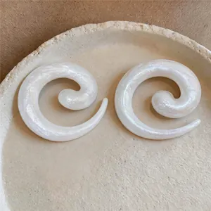 Detailed macro view of elegant iridescent white spiral earrings on a ceramic plate