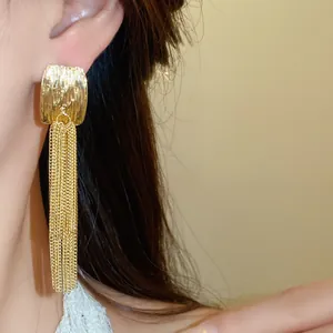 Macro view of French style gold pleated square earrings with double layer chain tassels