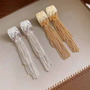 Detailed view of gold and silver pleated square earrings featuring long chain tassels.