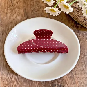 Detailweergave van een stijlvolle rode retro haarclip met witte stippen op een bord
