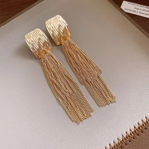 Detailed view of elegant gold pleated square stud earrings with long chain tassels