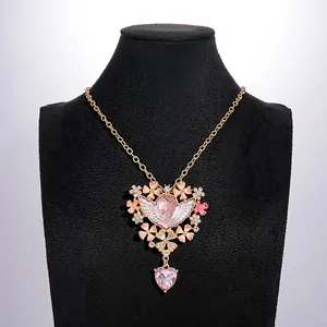 Close-up van een vintage engelketting met roze bloemen, hart hanger en glanzende strass.