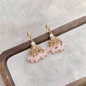 Detailed view of ethnic style earrings featuring pink bead tassels and gold zircon hooks