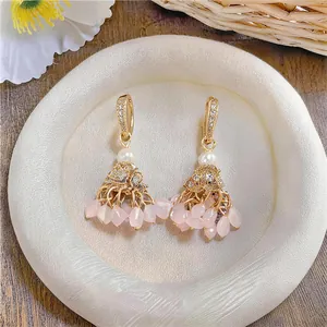 Detailed close-up of ethnic gold-plated earrings featuring pink tassels and zircon hooks
