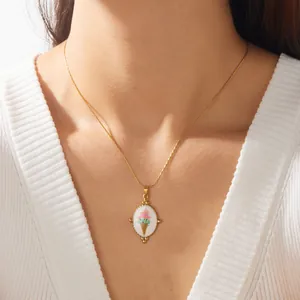 Close-up of a sweet enamel ice cream pendant necklace worn on a delicate gold chain.