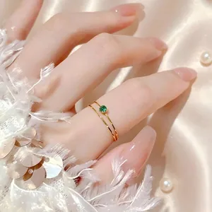 Elegante Nahaufnahme eines zierlichen 1mm goldfarbenen Titanrings mit grünem Zirkon