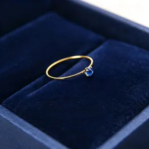 Nahaufnahme eines 1 mm goldfarbenen Titanstahlrings mit blauem Zirkonia-Stein in Box