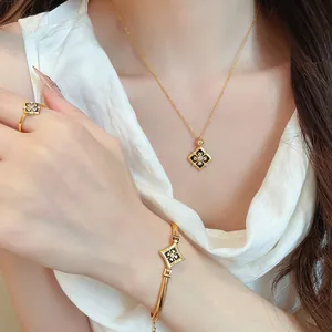 Parure de bijoux dorés avec collier, bracelet et bague fleur en zircon sur modèle.