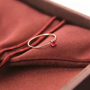 Nahaufnahme eines roségoldenen Rings mit einem runden roten Edelstein in einer Fassung