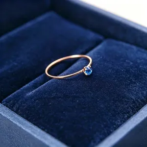 Nahaufnahme eines 1mm dünnen Roségold-Rings mit blauem Zirkonia in einer Samtbox