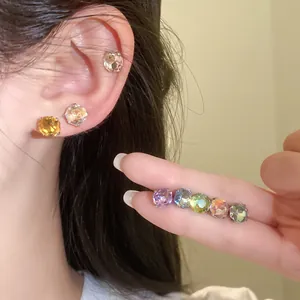Gros plan de boucles d'oreilles en cristal multicolore sur l'oreille et la main