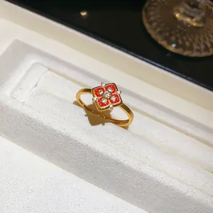 Gros plan d'une bague plaquée or 24K avec fleur en émail rouge et zircons brillants.