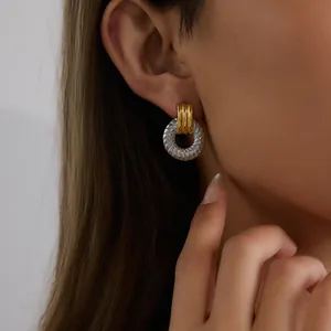 Gros plan élégant de boucles d'oreilles créoles bicolores dorées et argentées portées à l'oreille.