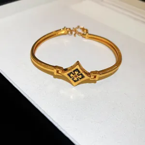 Vue détaillée d'un bracelet jonc plaqué or 24 carats avec un motif floral en émail noir