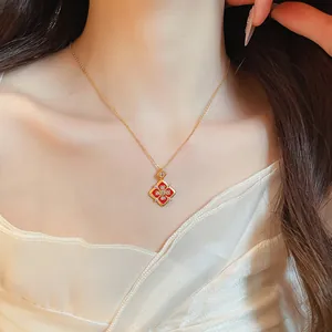 Gros plan d'un collier plaqué or avec un pendentif fleur rouge et des zircons brillants