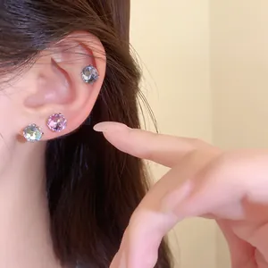 Gros plan de boucles d'oreilles clous rondes élégantes en acier inoxydable sur l'oreille