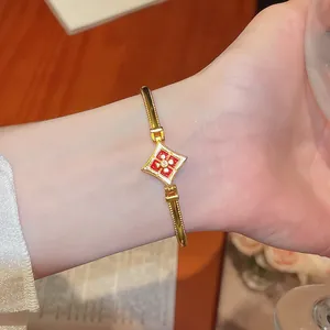 Vue détaillée d'un élégant bracelet plaqué or 24 carats avec motif fleur en zircon rouge.