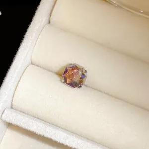 Détail macro d'une boucle d'oreille en cristal irisé dans un écrin à bijoux en velours beige
