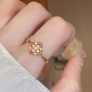 Gros plan d'une bague fleur élégante plaquée or avec émail rouge et zircons brillants