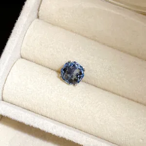 Gros plan d'une boucle d'oreille à pierre bleue dans un écrin en velours blanc