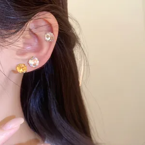 Gros plan détaillé de boucles d'oreilles rondes en acier inoxydable et strass sur l'oreille